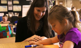 Kindergarten Teacher smiling at her studen while she's drawing